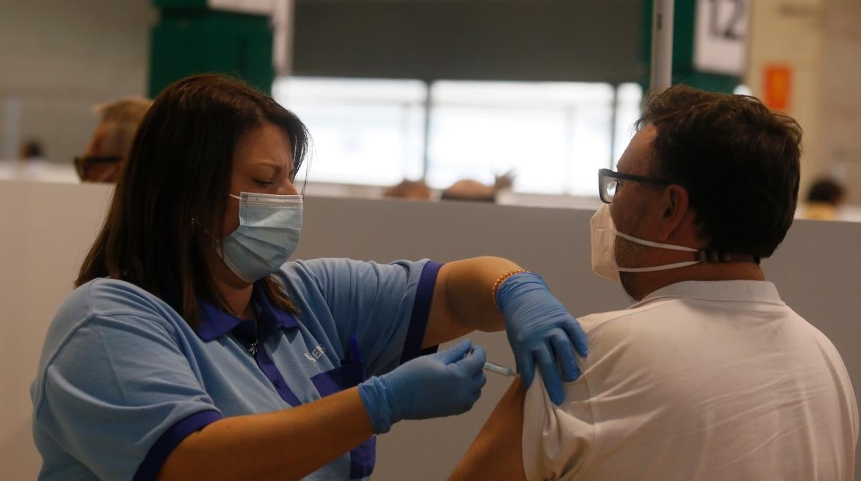 Una sanitaria vacuna a un hombre en el estadio de la Cartuja
