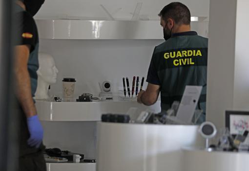 Un agente revisa productos como cámaras y bolis espía que había en la tienda