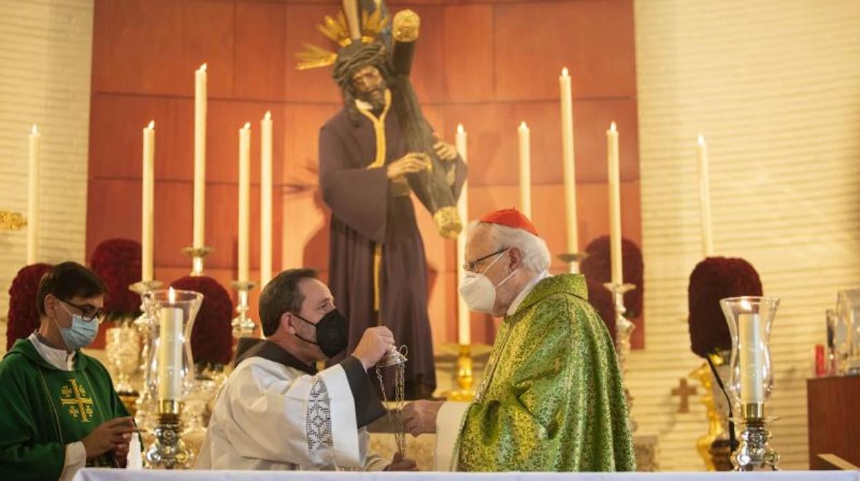 Monseñor Amigo, revestido al inicio de la eucaristía, ayudado por el hermano Pablo, ante el Señor del Gran Poder en la Candelaria