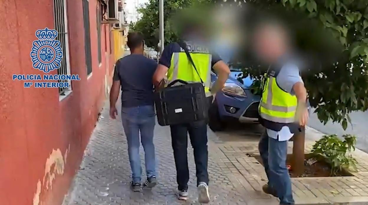El detenido, saliendo de su casa, es acompañado por dos agentes a dependencias policiales