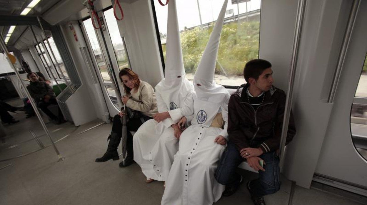 Dos nazarenos viajan en el metro en la Semana Santa de 2019