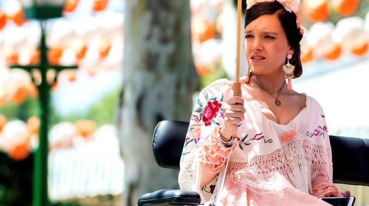 Una joven se resguarda del Sol con una sombrilla montada en un coche de caballos