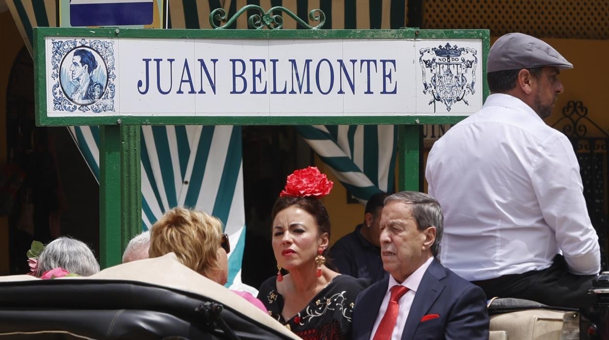 Varias personas pasan, montados en un coche de caballos, por el cartel de la calle Juan Belmonte