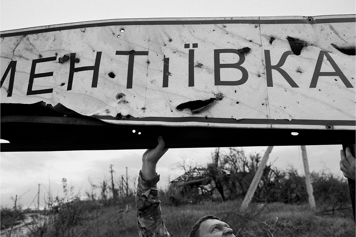 Kharkiv, Ucrania: Un soldado con la ayuda del resto de los miembros de su patrulla levanta el cartel destruido del pueblo de Dementiyivka. Dementiyivka se encuentra a cinco kilómetros de la frontera rusa. Aunque es una zona liberada, sigue siendo atacada por la artillería rusa y pequeños comandos rusos realizan pequeñas incursiones para atacar a las tropas ucranianas desplegadas en la zona.