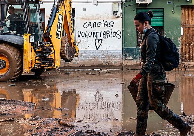 Una vecina camina entre el lodo y los escombros en Paiporta.