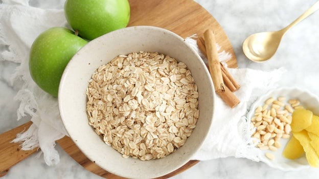 Bodegón con copos de avena, canela y manzana verde.