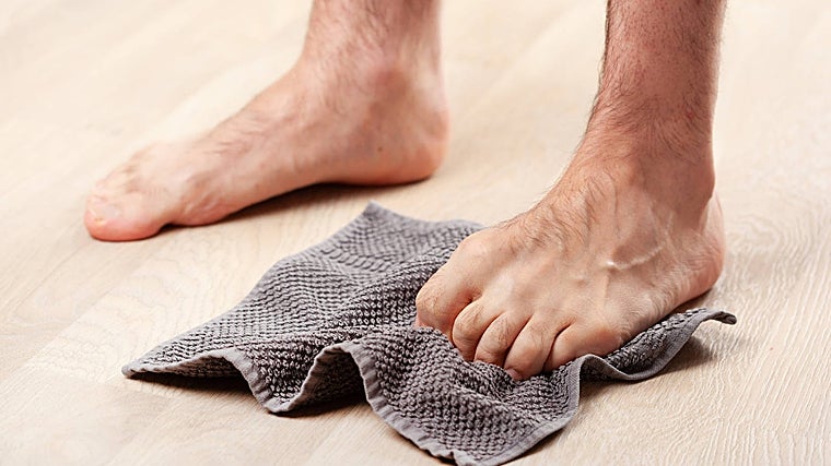 Intenta agarrar la toalla con el pie.