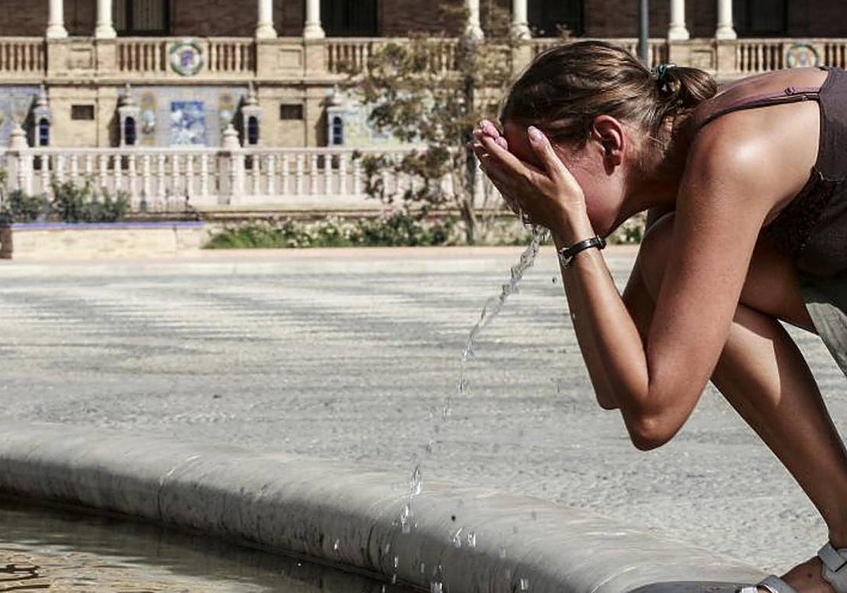 Una joven se refresca en la fuente de la Plaza de España en plena ola de calor