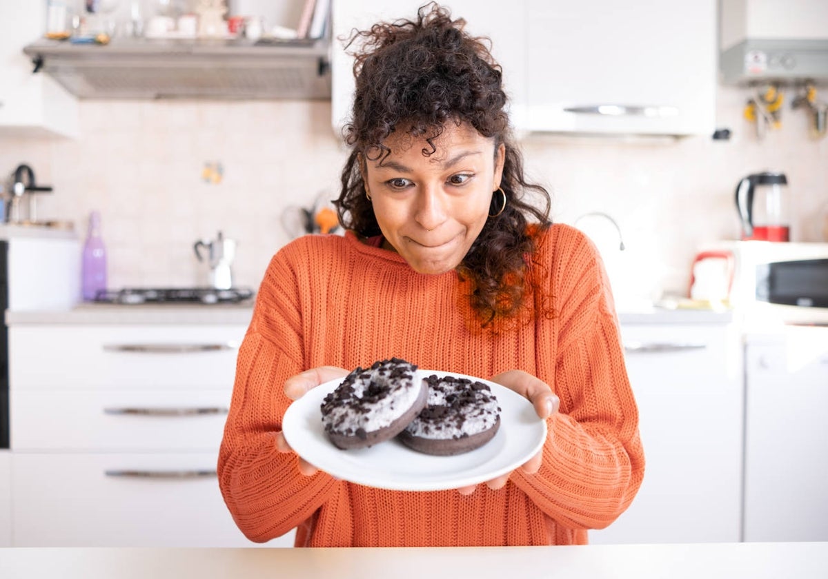 Una mujer mira dos donuts con deseo