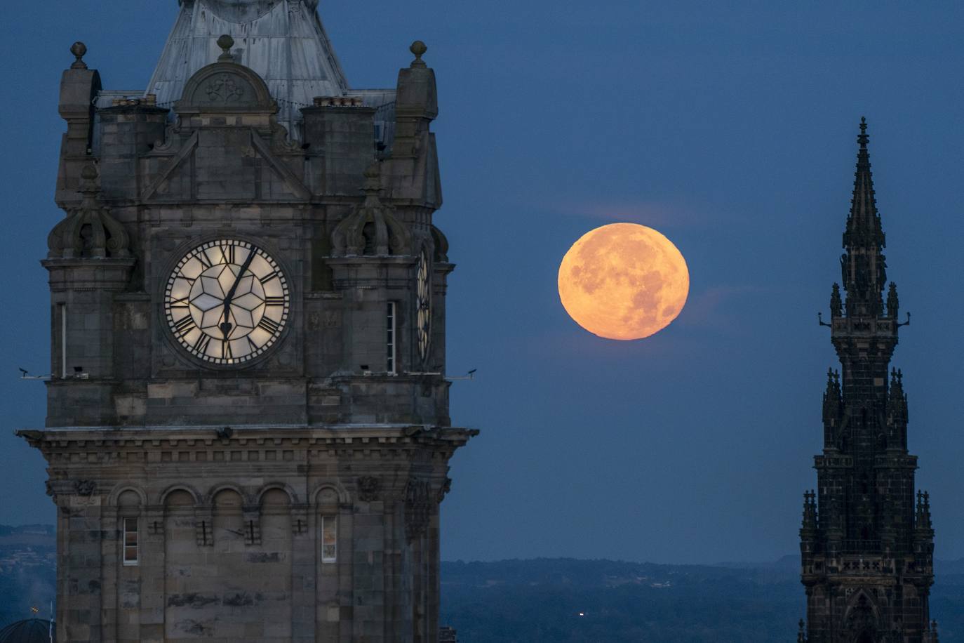 La Superluna Azul se pone entre el Reloj de Balmoral y el Monumento a Scott, en Edimburgo