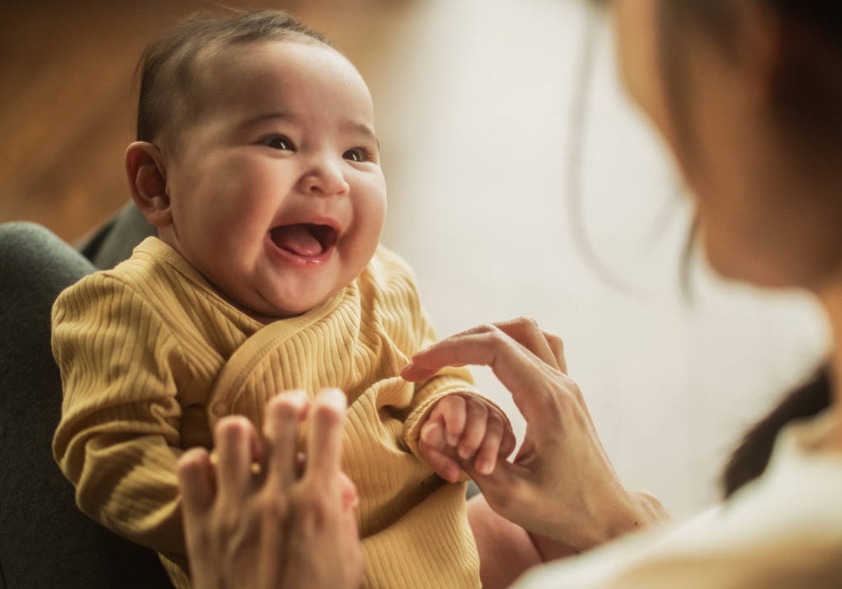 Un bebé se ríe por las cosquillas que le hace su madre, en una imagen de archivo