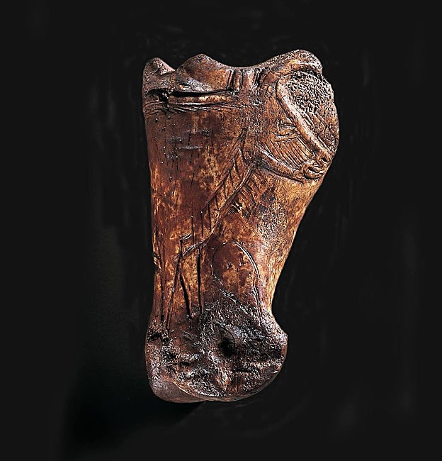 Falange de uro con grabados del propio animal y una cara humana, abajo