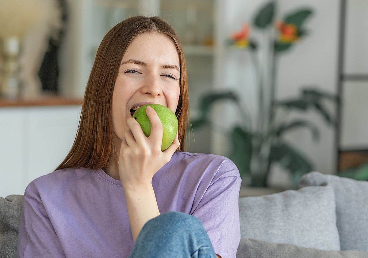 Una joven muerde una manzana