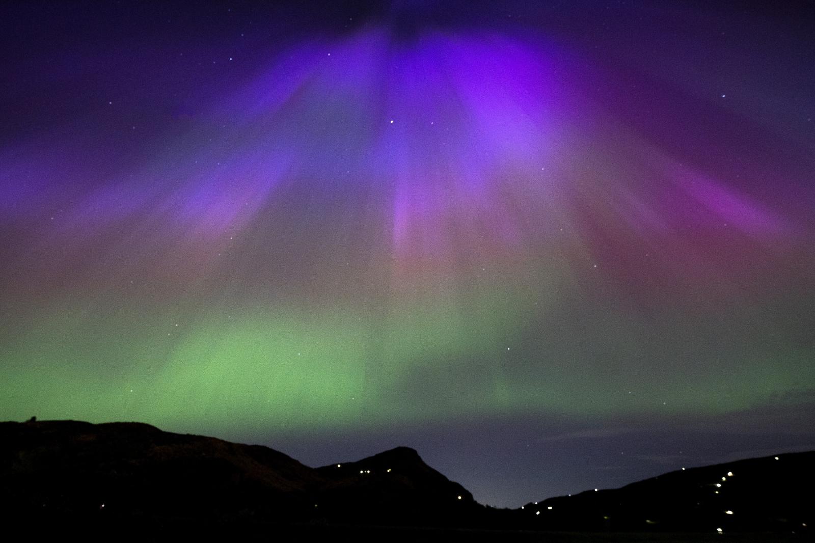 La aurora boreal aparece sobre Arthur's Seat y Salisbury Crags en Holyrood Park, Edimburgo