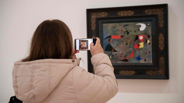 Un mujer hace una foto a una de las obras de Miró