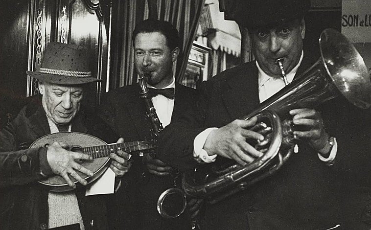 Imagen principal - Arriba, Picasso, Paco Muñoz y el anticuario Affentranger en su negocio, fotografiados por Lucien Clergue. Arlés, 30 de marzo de 1959. Sobre estas líneas, a la izquierda, Pablo Picasso y un taxista en el aeropuerto de Niza, fotografiados por Lucien Clergue, 20 de agosto de 1965. A la derecha, Pablo Picasso en La Californie con un sol realizado con hoja de palmera comprado en la Feria de Ramos en la Rambla Cataluña de Barcelona, regalo del matrimonio Gili-Torra 