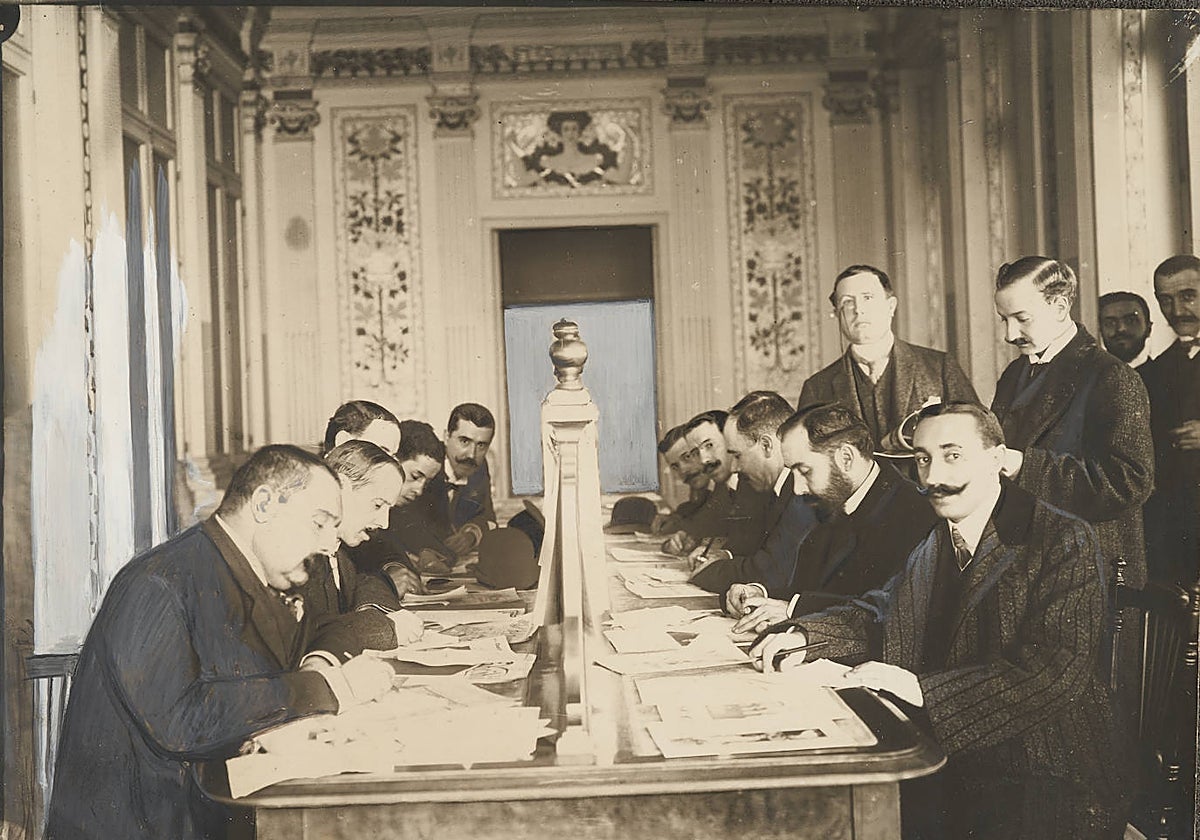 Los reporteros políticos de los diarios madrileños, copiando la nota oficial en el salón de la revista Blanco y Negro y ABC. Azorín, de pie el primero por la izquierda.