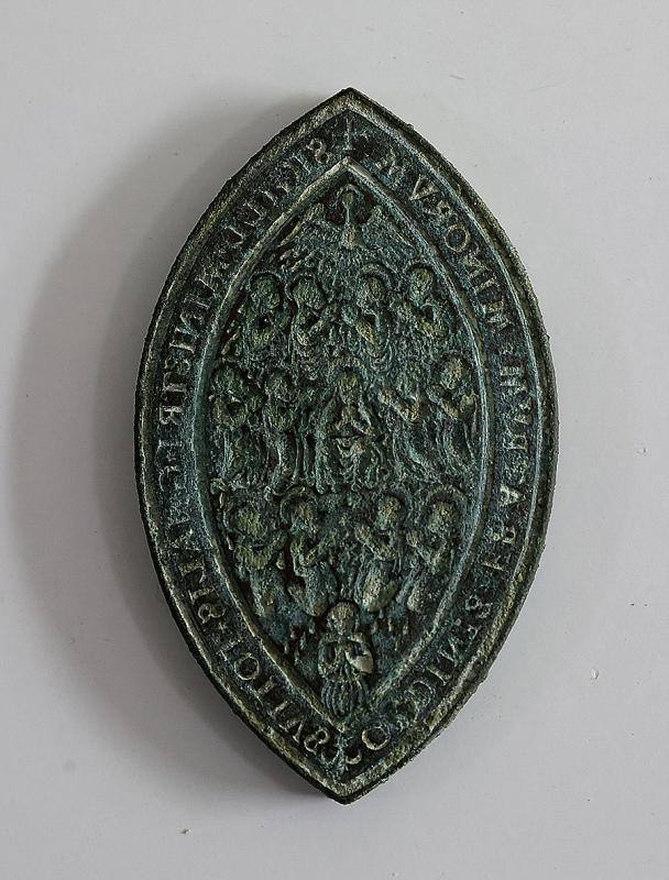 Matriz de un sello del superior de la orden franciscana hallado en la cimentación de la armería de Felipe II, datada en el siglo XVI.  En ella se ve a la Virgen María rodeada de los doce apóstoles bajo el Espíritu Santo, con una leyenda en latín, escrita de forma inversa para que se leyera correctamente en la impronta de cera.  