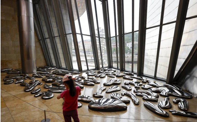 Imagen principal - Arriba, 'Nubes' de Kusama en el atrio. Al fondo, el estanque del exterior, que se ha inundado con más de 400 lunares rojos flotantes en homenaje a la artista. Sobre estas líneas, dos de las piezas de Yayoi Kusama en las salas del Guggenheim de Bilbao