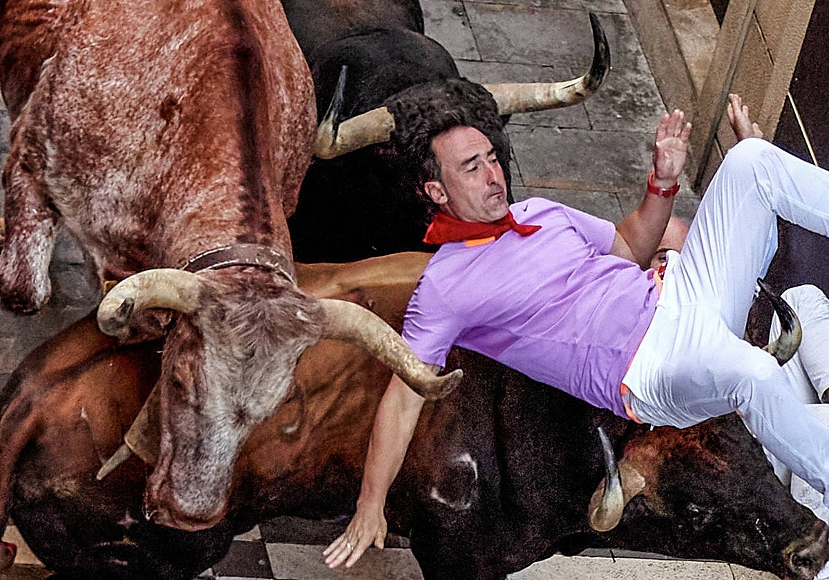 Un mozo es volteado por un toro de la ganadería de Fuente Ymbro al inicio de la calle de la Estafeta durante el cuarto encierro de los sanfermines 2023