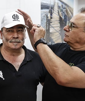 Imagen secundaria 2 - Chimo Bayo cortando el bacalao en la primera foto. En la segunda, muestra su anillo 'hu-ha'; en la última, con el dueño del restaurante 'El rey del bacalao'