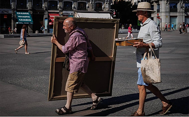 Imagen principal - Arriba, Antonio López, portando el lienzo en blanco hasta el centro de la Puerta del Sol, acompañado por su amigo y pintor Isidro Brunete, que lleva los bártulos. Sobre estas líneas, a la izquierda, el pintor midiendo meticulosamente antes de coger el pincel. A la derecha, detalle de su antebrazo izquierdo, donde lleva escrito el lugar exacto desde el que pinta: en la losa 9-10 
