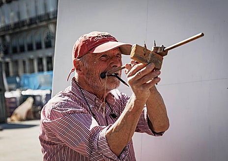 Imagen secundaria 1 - Arriba, Antonio López, portando el lienzo en blanco hasta el centro de la Puerta del Sol, acompañado por su amigo y pintor Isidro Brunete, que lleva los bártulos. Sobre estas líneas, a la izquierda, el pintor midiendo meticulosamente antes de coger el pincel. A la derecha, detalle de su antebrazo izquierdo, donde lleva escrito el lugar exacto desde el que pinta: en la losa 9-10 