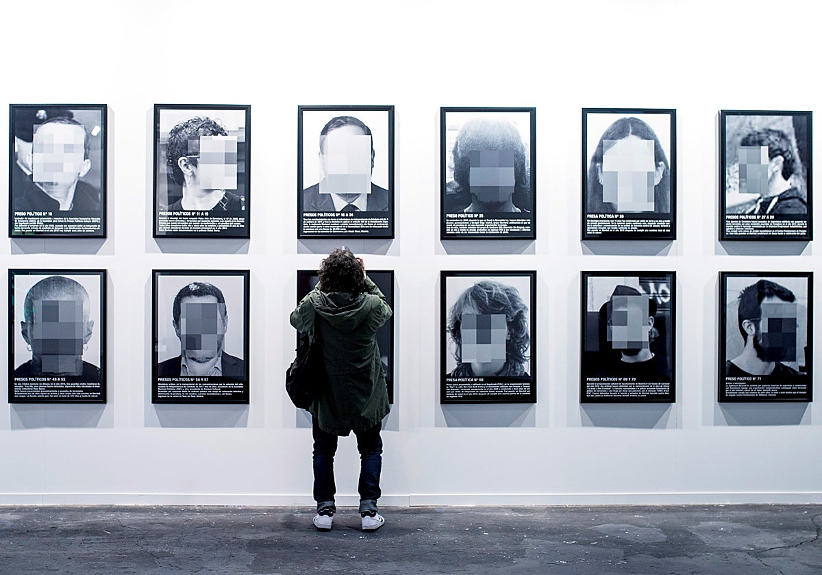 Un hombre toma fotos de las imágenes de la serie 'Presos políticos en España', de Santiago Sierra en ARCO 2018