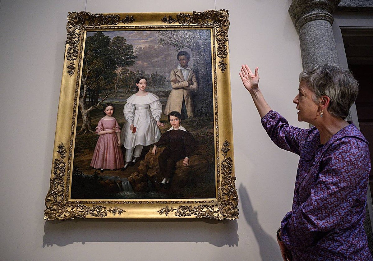 La conservadora Sylvia Yount muestra el cuadro de Jacques Amans, con Bélizaire