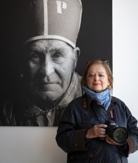 Imagen secundaria 2 - Arriba, Cristina García Rodero, en acción en La Endiablada. Sobre estas líneas, a la izquierda, posando junto con un fotógrafo ambulante de Jaén y gran admirador, que deseaba hacerse una foto con ella; a la derecha, la fotógrafa ante un retrato de un diablo que hizo hace años y que donó al pueblo de Almonacid