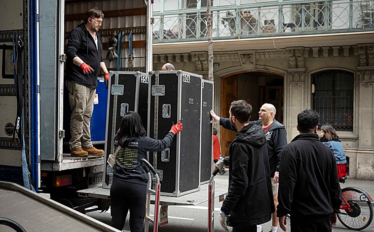 Imagen principal - Arriba e izquierda: El equipo técnico de la NSO descarga los instrumentos en la puerta del Palau de la Música Catalana, mientras que en la derecha lo descarga en el Auditorio Nacional de Madrid