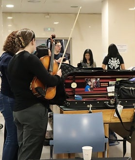 Imagen secundaria 2 - Loewi Lin se corta las uñas antes del concierto y se toma un café para no perder las fuerzas junto a un compañero mientras otros miembros de la orquesta se van preparando 