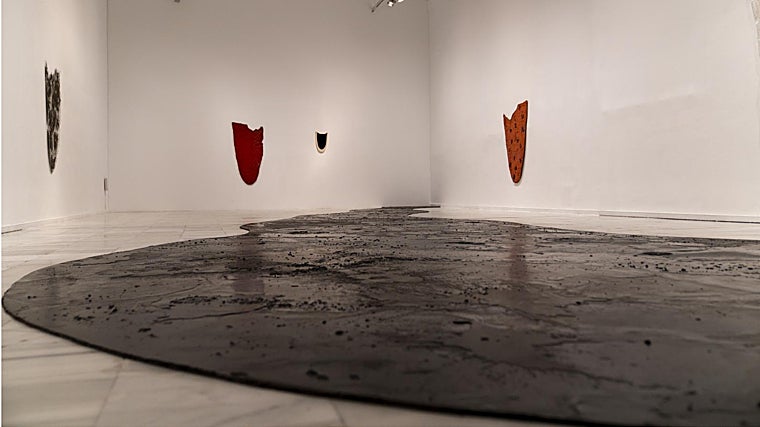 En primer plano, 'Gran lengua de betún', de Eva Lootz, en una de las salas de la exposición