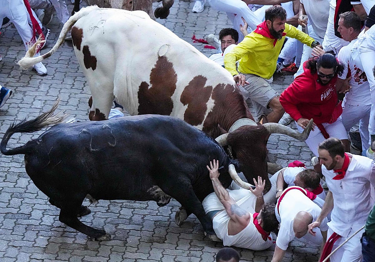 Unos corredores se protegen al paso de varios toros de la ganadería Cebada Gago durante el segundo encierro de los Sanfermines en Pamplona