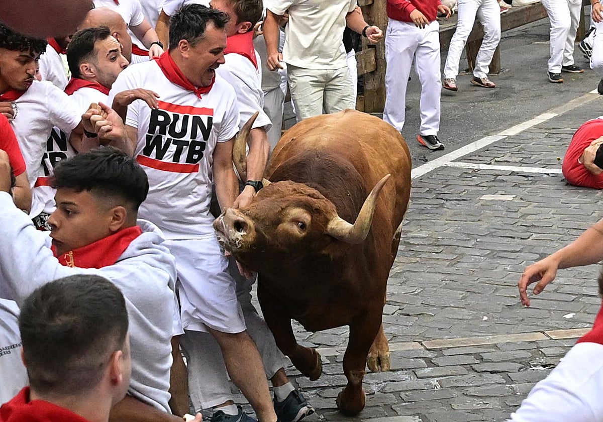 Un mozo evita a uno de los toros de la ganadería Jandilla durante el quinto encierro de los Sanfermines este viernes en Pamplona