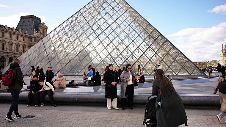 Turistas posando ante la entrada del Louvre