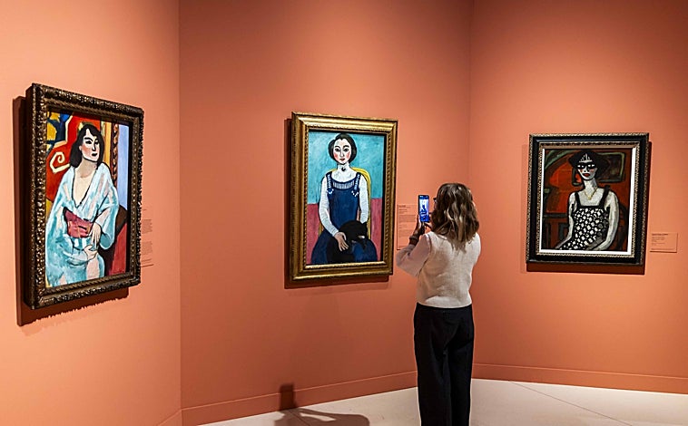 Imagen principal - Arriba, una joven junto a tres obras en la exposición ('La argelina' y 'Marguerite con gato negro', ambas de Matisse, e 'Yvette o el vestido a cuadros', de Chabaud). Sobre estas líneas, a la izquierda, 'Autorretrato' de Matisse, de 1900, y 'El lujo I', de Matisse, 1907. A la derecha, 'Interior con pecera', 1914, de Matisse. Centro Pompidou, París