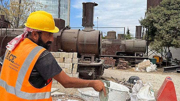 Um trabalhador usa cal do único fabricante do Líbano. Várias locomotivas e uma caixa d'água podem ser vistas ao fundo. Estamos bem em frente ao porto, então a explosão causou muitos danos.