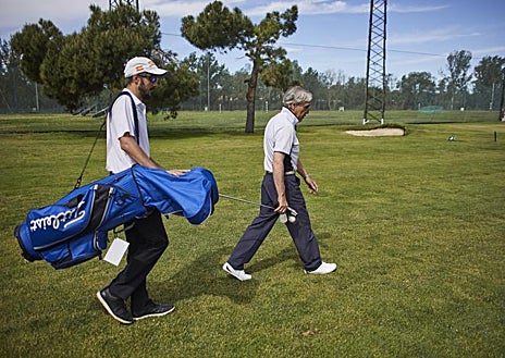 Imagen secundaria 1 - La colocación, clave . Conocedor de la pegada del jugador, su guía le sugiere el palo adecuado y le coloca correctamente para que la la bola vuele en la dirección elegida.  Unidos entre golpes . Con la ayuda de un palo de golf, que cada uno agarra desde un extremo, los dos se encaminan al lugar donde tienen que efectuar el siguiente golpe.  En el green, precisión . Si la colocación en los golpes de vuelo es importante, mucho más a la hora de patear. Además, miden los pasos hasta el hoyo para calcular la fuerza