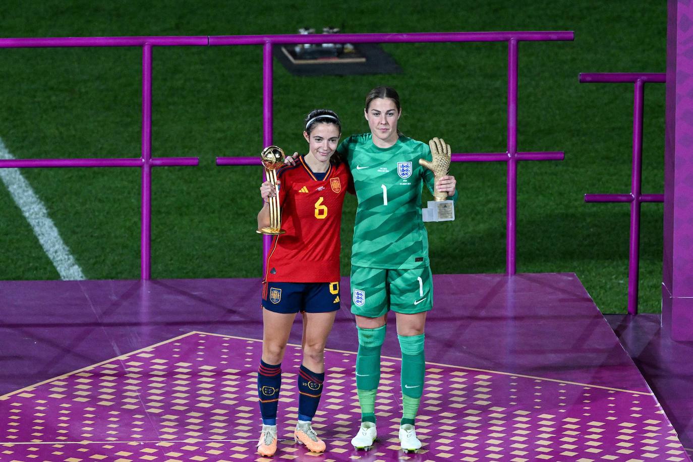 La centrocampista española Aitana Bonmati (izq.) sostiene el trofeo en el podio del Balón de Oro de la FIFA y abraza a la guardameta inglesa Mary Earps, que sostiene el Guante de Oro de la FIFA, durante los Juegos Olímpicos de Australia y Nueva Zelanda 2023