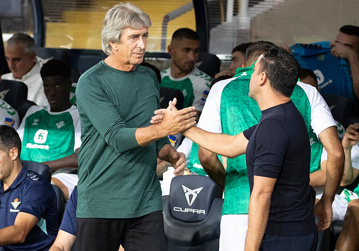 Los técnicos del FC Barcelona, Xavi Hernández y del Betis, el chileno Manuel Pellegrini, se saludan antes del inicio del encuentro correspondiente a la quinta jornada de primera división disputado  en el estadio Olímpico de Montjuic, en Barcelona