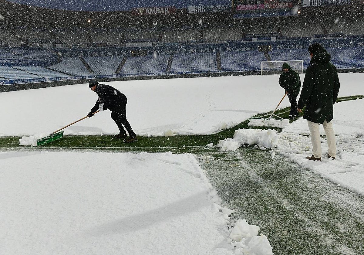 Operarios de La Romareda tratan de apartar la nieve del césped