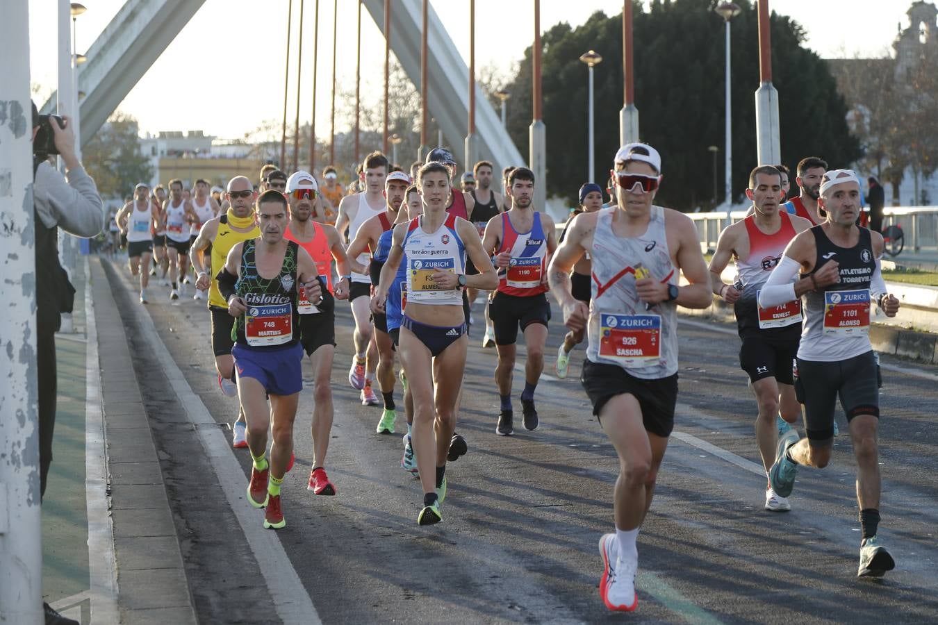 Corredores del maratón a su paso por el puente de la Barqueta