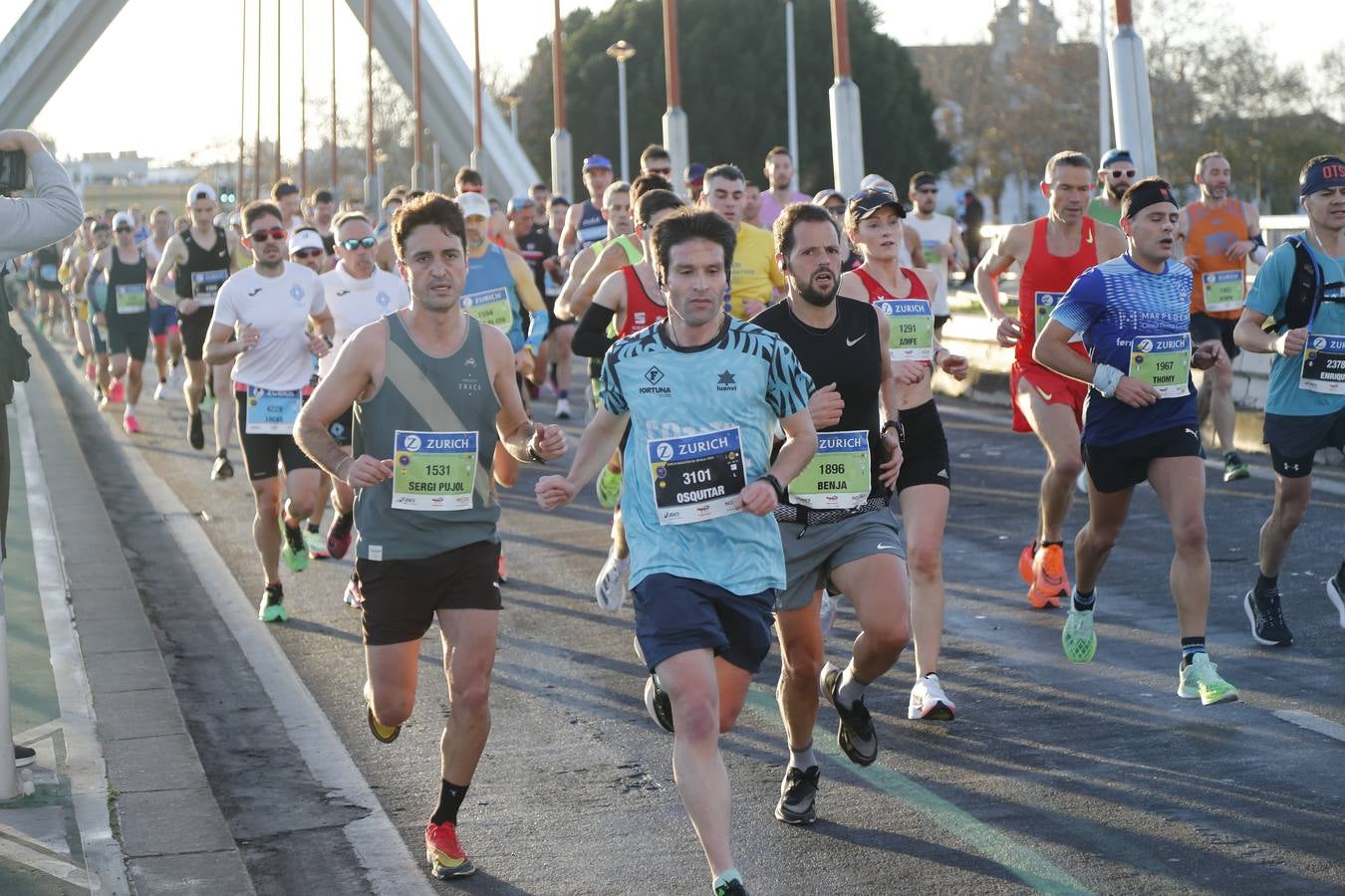 Corredores del maratón a su paso por el puente de la Barqueta
