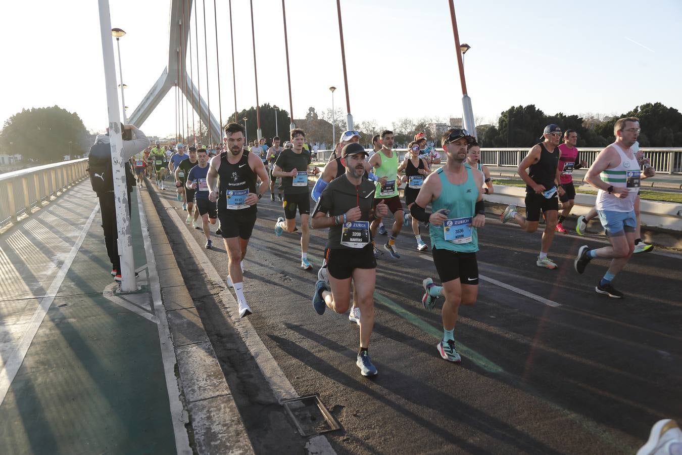 Corredores del maratón a su paso por el puente de la Barqueta