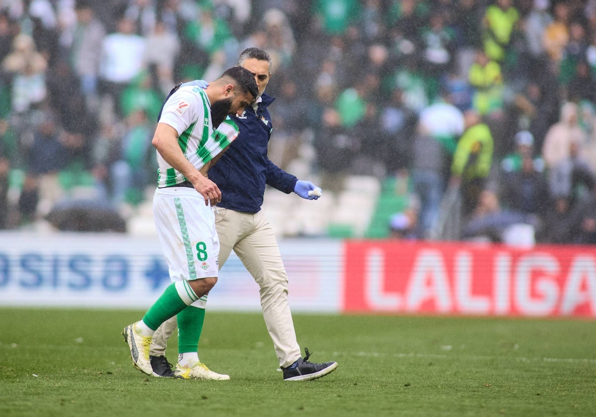 Nabil Fekir sale del terreno de juego para ser atendido por el doctor Álvarez en el Betis - Athletic