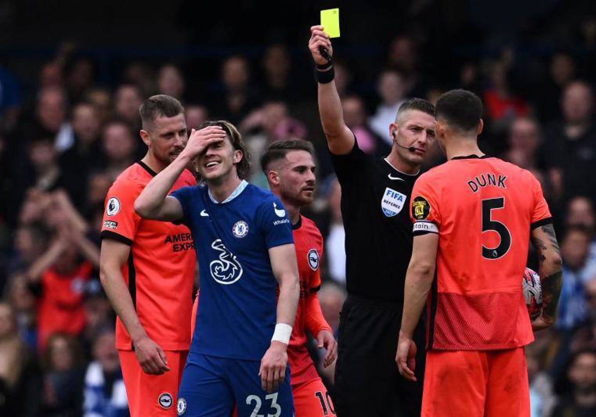 El árbitro inglés Robert Jone muestra una cartulina amarilla al jugador del Chelsea Gallagher durante un partido ante el Brighton de la temporada 2022-23