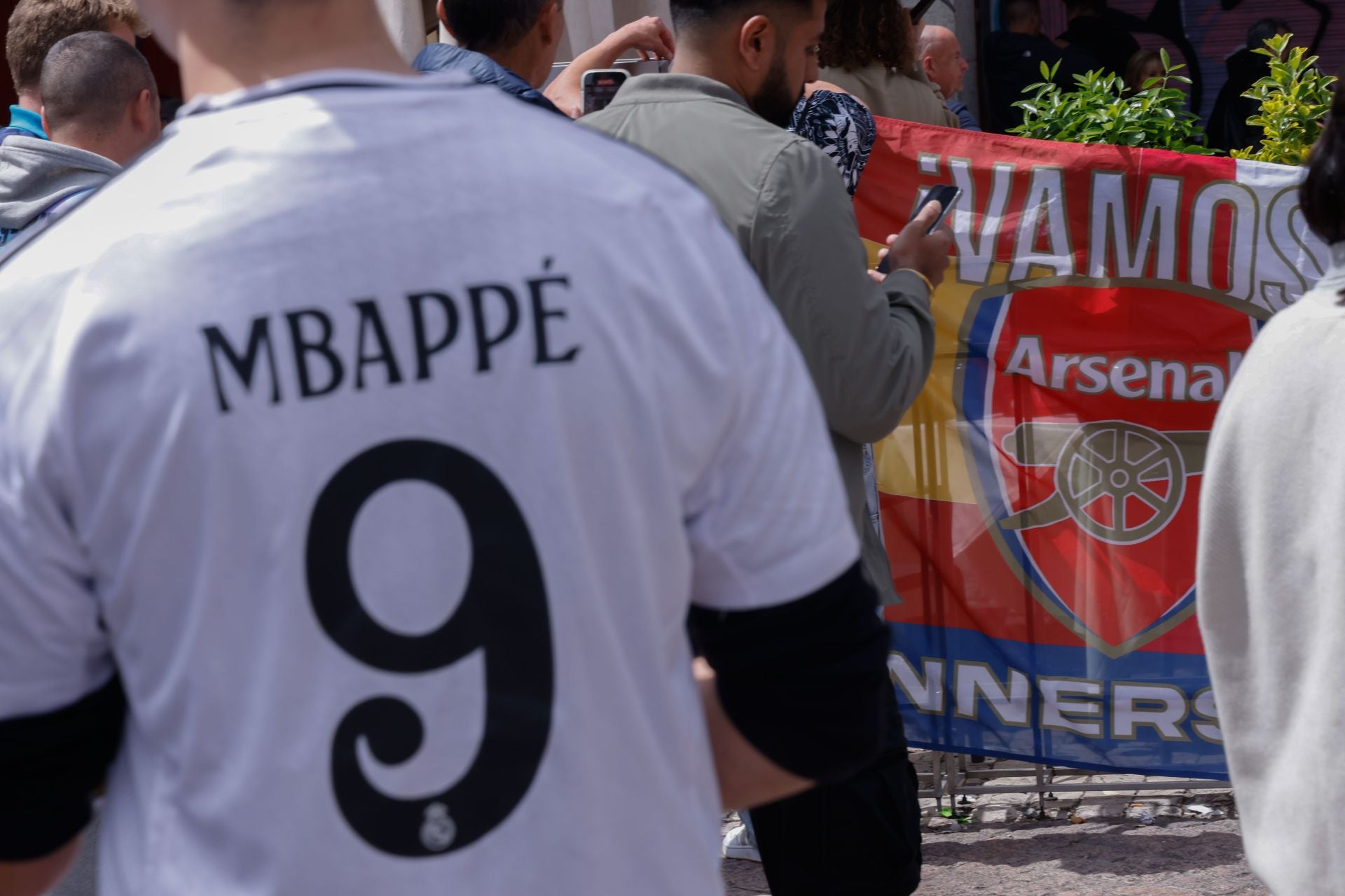 Un aficionado del Madrid con la camiseta de Mbappé y otro español del Arsenal con una bandera de apoyo a su equipo. 
