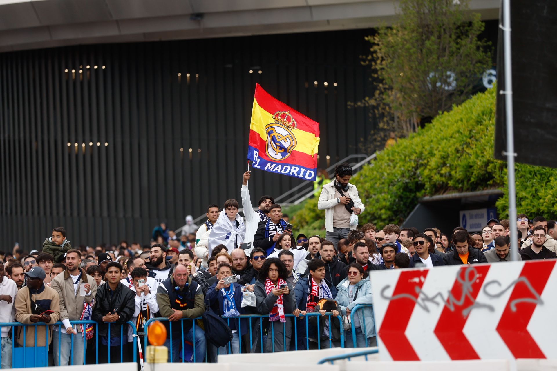 Aficionados sostienen una bandera del Real Madrid mientras esperan el autobús del equipo.