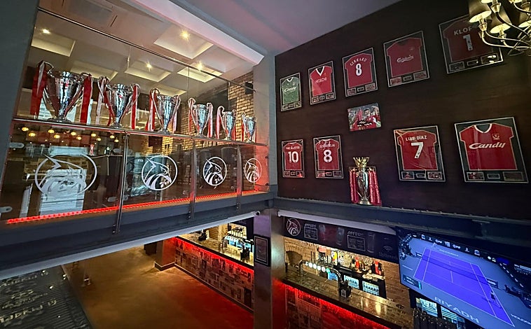 Imagen principal - Decoración y recortes en el bar Reds, uno de los principales de los hinchas del Liverpool. A la derecha, las botas de Xabi firmadas